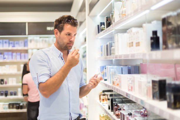 Elegant man choosing the perfume in retail store.